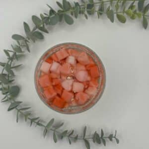 Kaars in doorzichtige glazen pot. Onderste laag is wit kaarsvet. Vervolgens doorzichtige gel met hartjes in verschillende rood tinten.