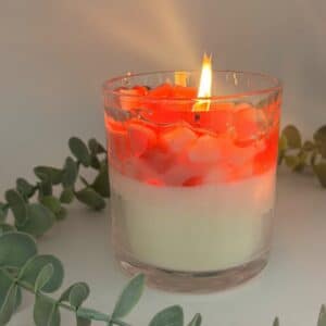 Kaars in doorzichtige glazen pot. Onderste laag is wit kaarsvet. Vervolgens doorzichtige gel met hartjes in verschillende rood tinten.