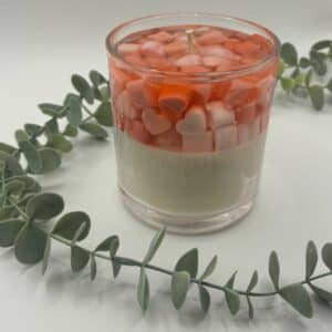 Kaars in doorzichtige glazen pot. Onderste laag is wit kaarsvet. Vervolgens doorzichtige gel met hartjes in verschillende rood tinten.