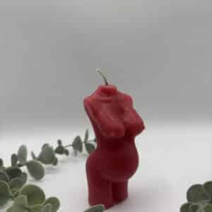 Een rode kaars in de vorm van een buste van een zwangere vrouw.