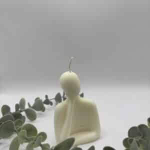 Een witte kaars in de vorm van groot mannetje die aan het denken is.