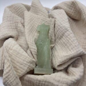 Een licht groene kaars in de vorm van een beeld van Venus zonder hoofd.