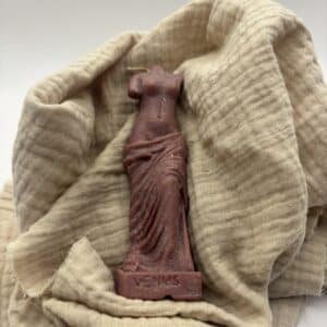 Een bordeaux kaars in de vorm van een beeld van Venus zonder hoofd.