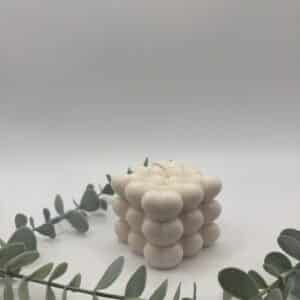 Een beige kaars in de vorm van een kubus met hartjes.