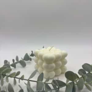 Een witte kaars in de vorm van een kubus met hartjes.