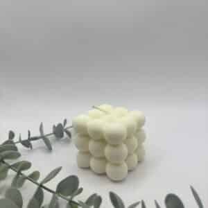 Een witte kaars in de vorm van een medium kubus met bolletjes.