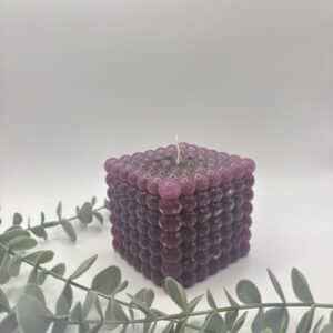 Een bordeaux kaars in de vorm van een grote kubus met bolletjes.