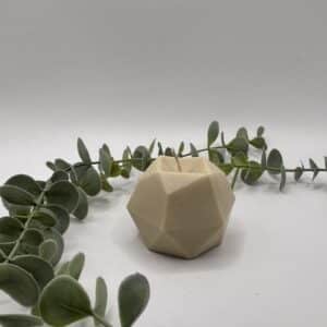 Een beige kaars in de vorm van een zeshoek.