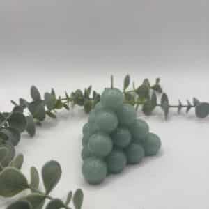 Een licht groene kaars in de vorm van een kleine piramide bestaande uit bolletjes.