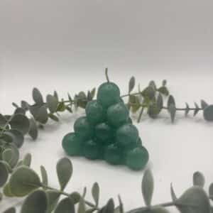 Een donker groene kaars in de vorm van een kleine piramide bestaande uit bolletjes.