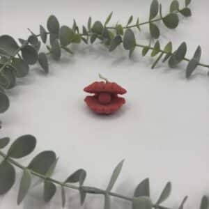 Een rode kaars in de vorm van een schelp met een parel in.