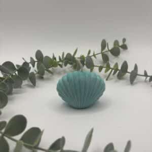 Een turquoise kaars in de vorm van een schelp.
