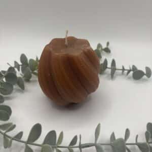 Een donker oker kleurige kaars in de vorm van een bol met groeven.