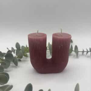 Een rode kaars in de vorm van een U met groeven met twee lonten.