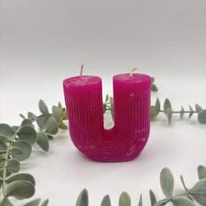 Een roze kaars in de vorm van een U met groeven met twee lonten.