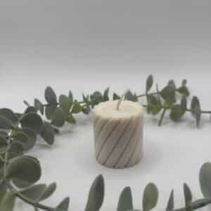 Een gebroken witte kaars in de vorm van een kleine cilinder met groeven.