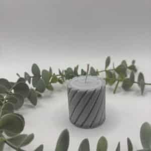 Een grijze kaars in de vorm van een kleine cilinder met groeven.