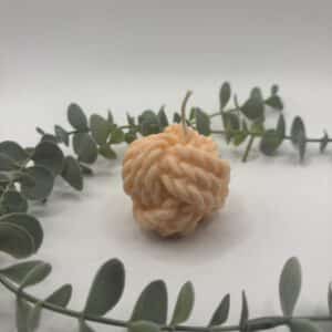 Een peach kaars in de vorm van een bol sjortouw.