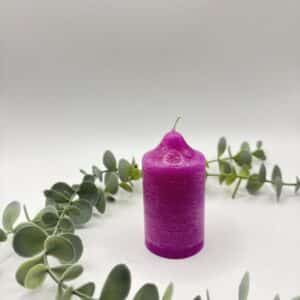 Een roze kaars in de vorm van een kleine cilinder.